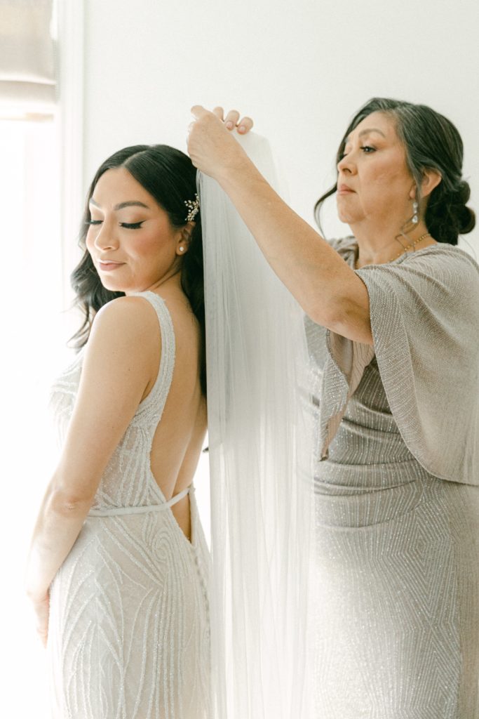 Mother of the bride helps the bride getting ready with her cathedral veil